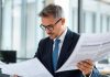 Business professional analyzing financial documents in an office.