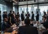 Professionals in suits discussing in a busy office setting.