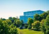 Modern office building in a green landscape with blue sky.