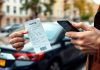 Person with parking ticket and smartphone on city street.