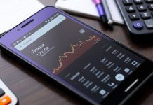 Smartphone with Google Finance app on a stylish desk.