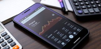 Smartphone with Google Finance app on a stylish desk.