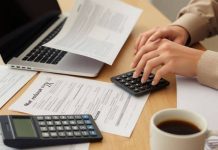 Person reviewing tax documents and laptop for refund status.