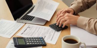 Person reviewing tax documents and laptop for refund status.