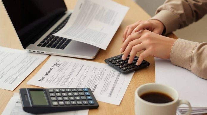 Person reviewing tax documents and laptop for refund status.